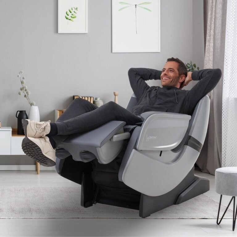 uomo sdraiato con le scarpe sulla poltrona massaggiante Casada Ecosonic - Argento in salotto