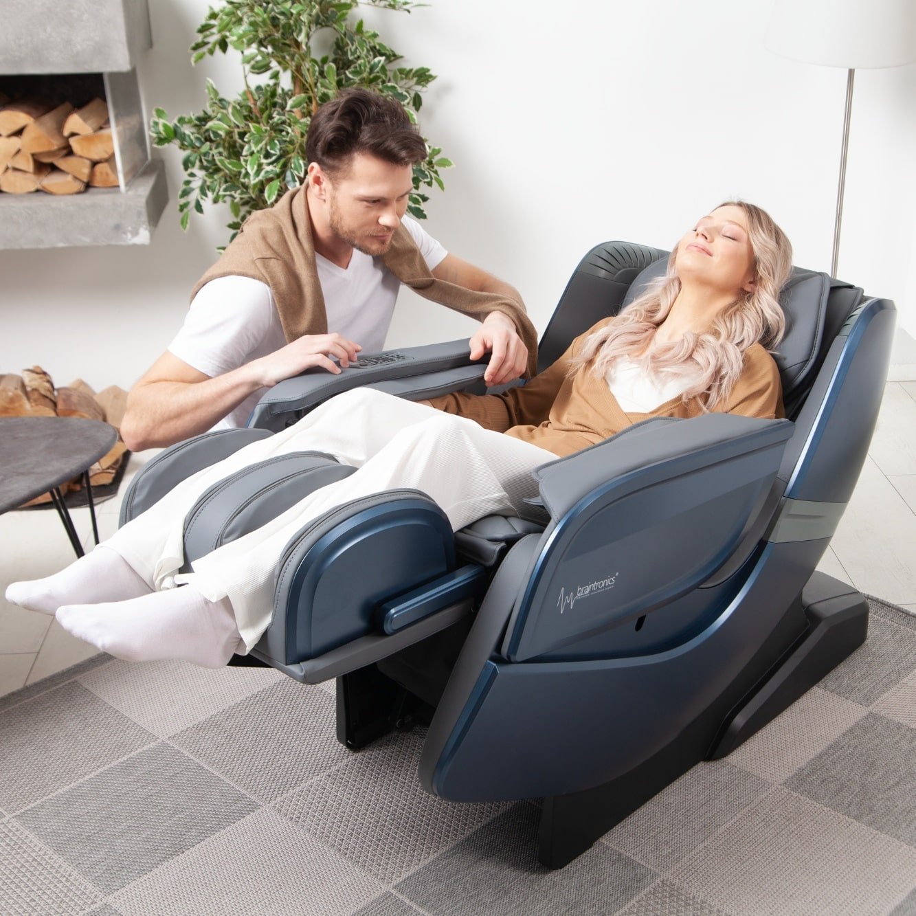 Frau liegt in Massagesessel Ecosonic - Blau mit Mann daneben kauernd