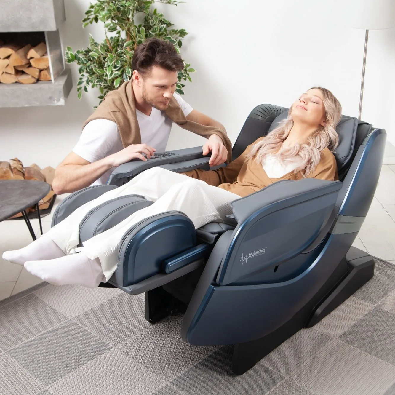 femme allongée dans un fauteuil de massage Ecosonic - Bleu avec un homme accroupi à côté du fauteuil