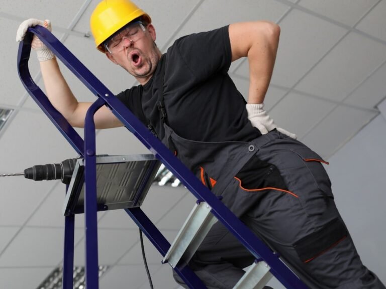trabajador en escalera que sufre lumbago agudo