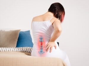 vrouw zittend op bed met hernia onderrug