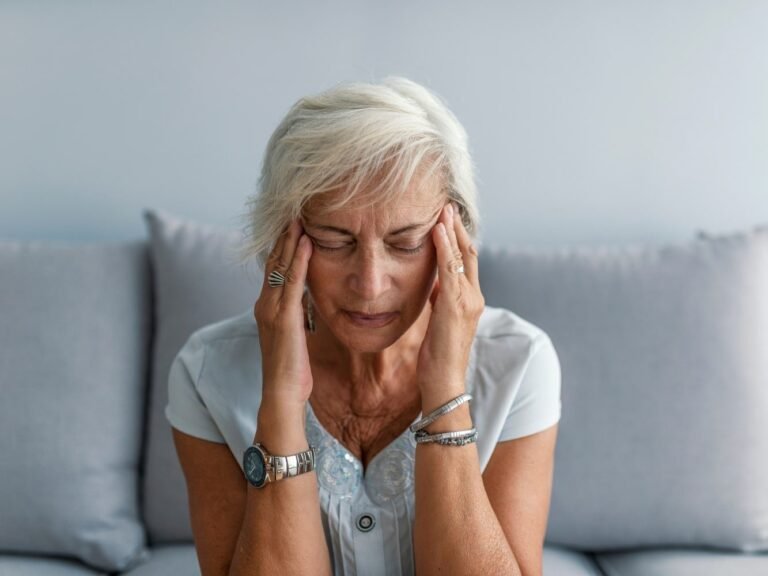 mujer en el asiento con dolor de cabeza