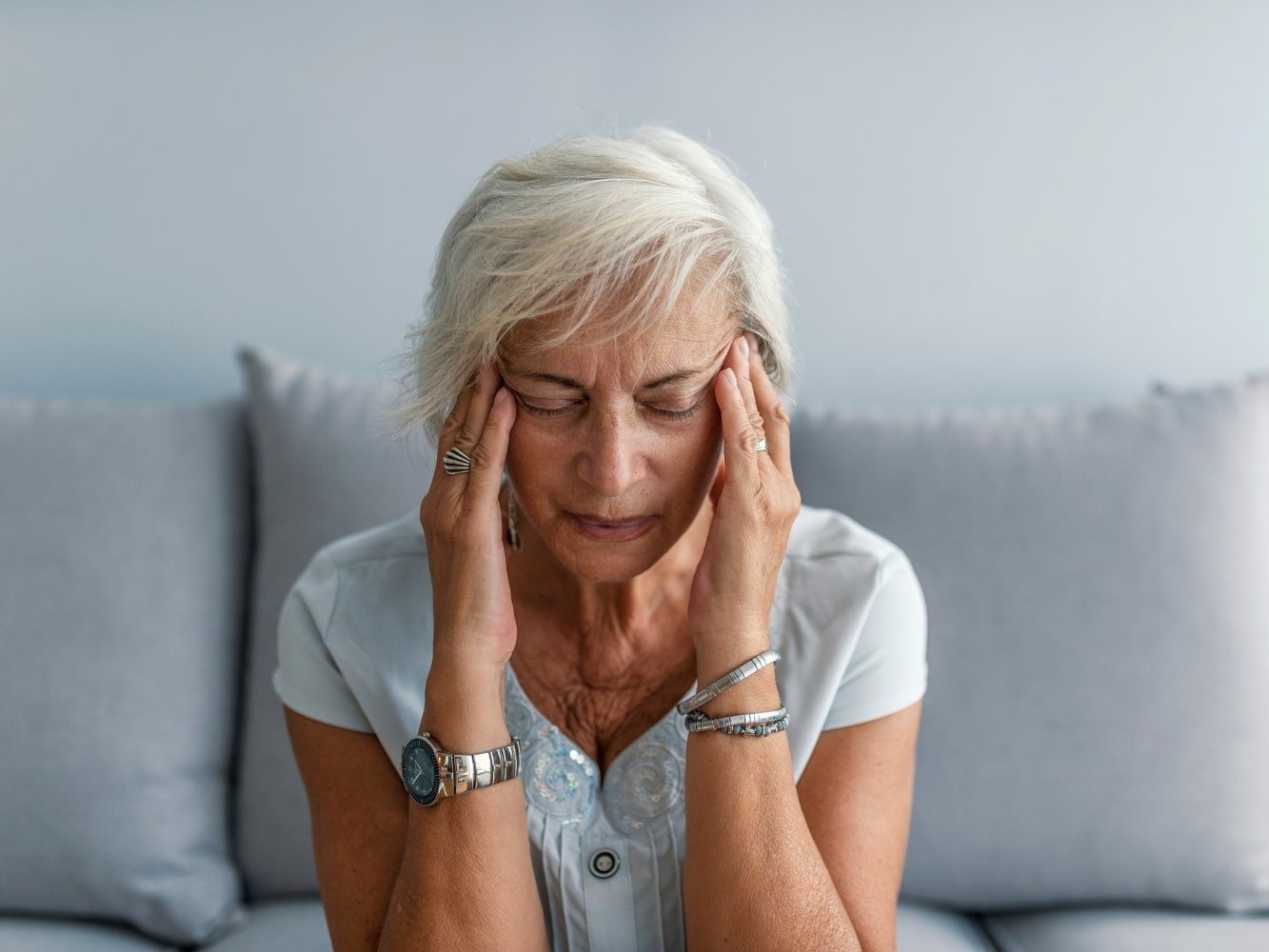 mujer en el asiento con dolor de cabeza