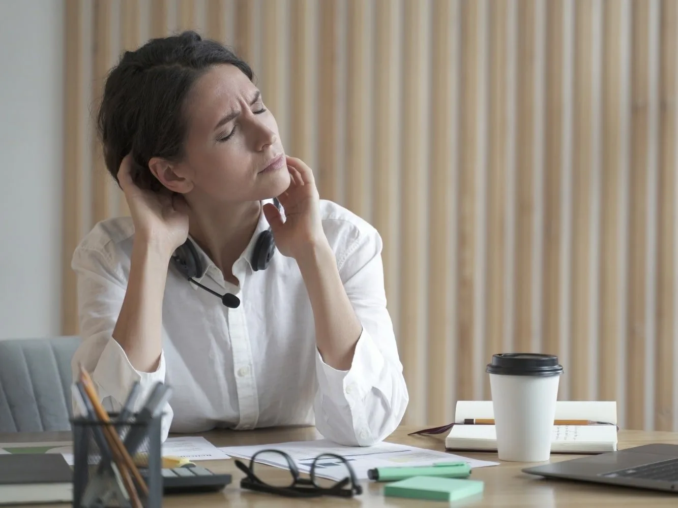 Mujer en su escritorio con reumatismo muscular y estrés
